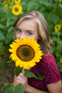 High School Senior playing with a sunflower at a sunflower field