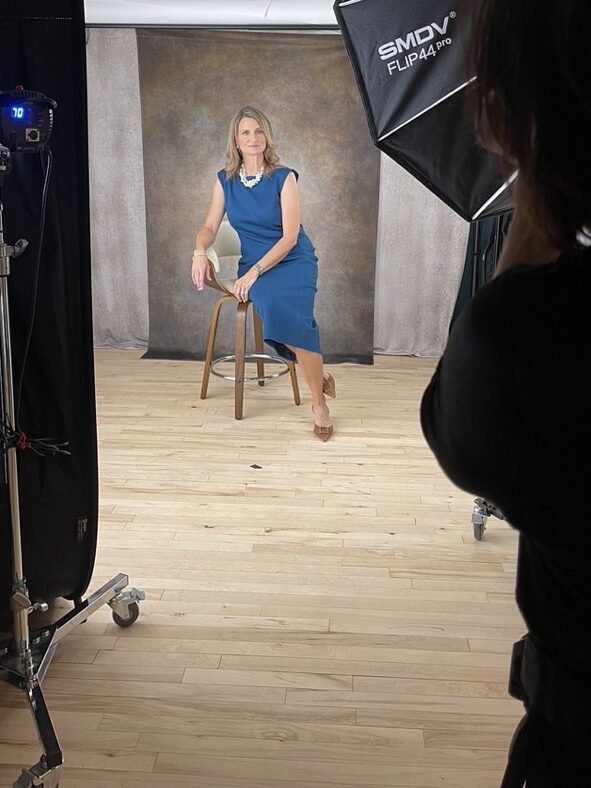 Woman business owner being guided into flattering pose during professional headshot session in studio
