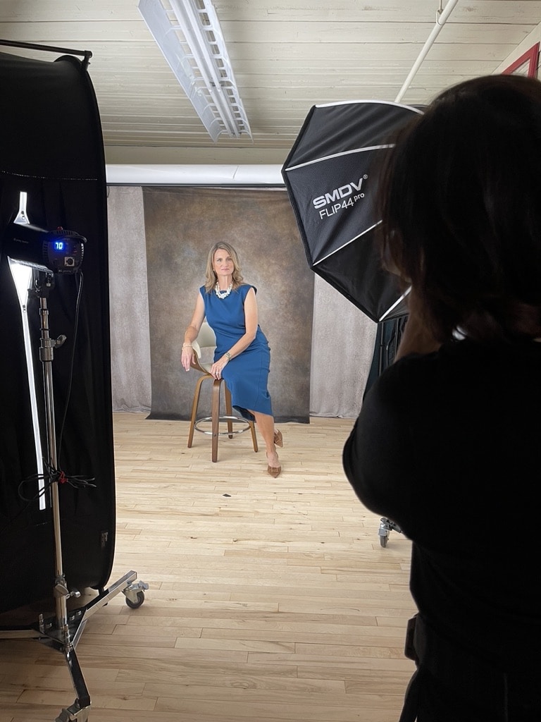 Woman business owner being guided into flattering pose during professional head shot session in studio